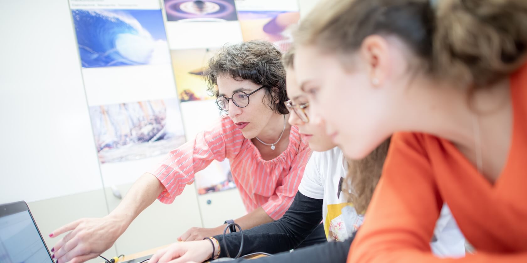 Lehrperson erklärt den Schülern etwas am Laptop